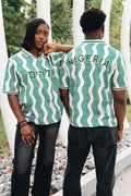 Heritage Jersey — two models wearing the jersey in cream/green wave pattern with Hebrew Elohim lettering, under an arch structure